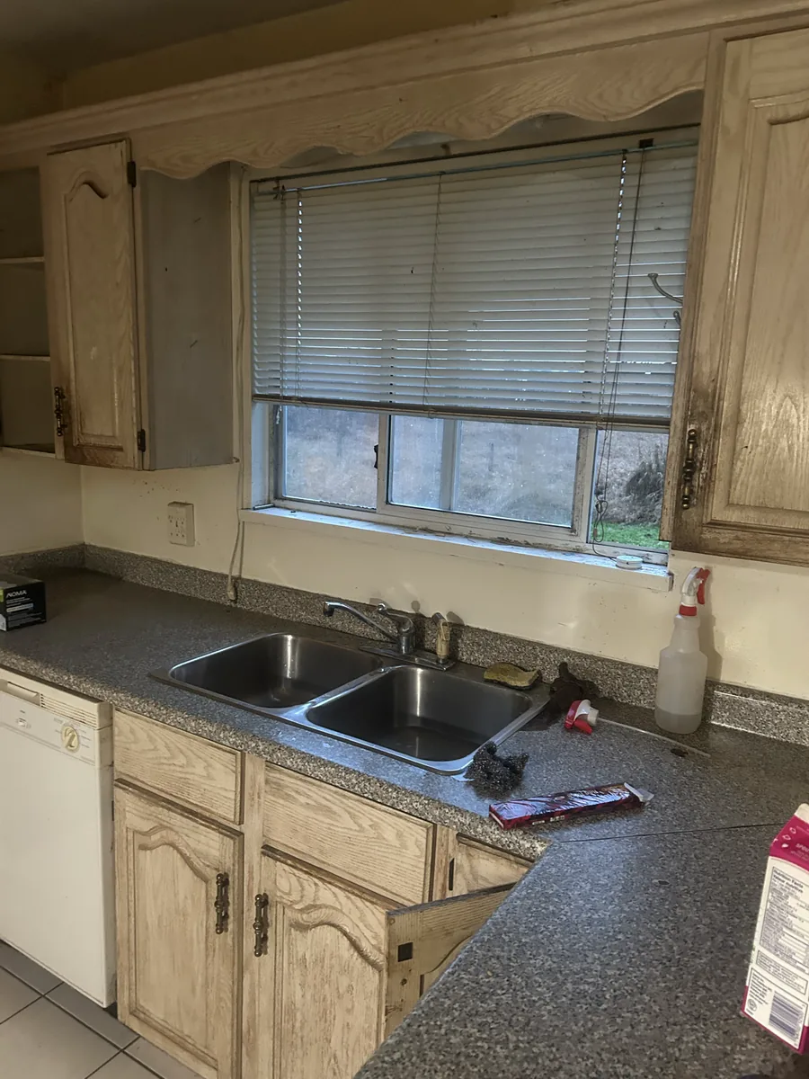 Kitchen with wooden cabinetry, a double sink, and a window above the countertop.